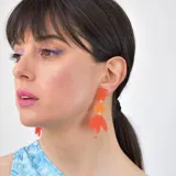 Aros colgantes con formas geométricas abstractas en color naranja y amarillo.
