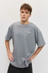Remera blanca de manga corta, corte oversize, con estampa en la espalda de una flor sobre fondo difuminado verde y blanco.