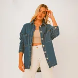 Camisa de jean celeste con botones blancos, corte holgado, mangas largas y bolsillos frontales.