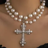 Collar de doble vuelta de perlas blancas con dije de cruz plateada con incrustaciones de perlas.