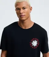 Remera negra de algodón con cuello redondo y manga corta, corte comfort. Presenta un pequeño estampado circular en el pecho con el logo de la banda Red Hot Chili Peppers.