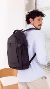 Mochila negra con compartimento principal, bolsillo frontal vertical, bolsillos laterales de red y correas ajustables con broches laterales. Cuenta con capacidad para notebook.