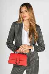 Cartera de cuero sintético color rojo, con solapa frontal y cierre metálico en forma de D. Tiene un asa superior y una correa de hombro ajustable.