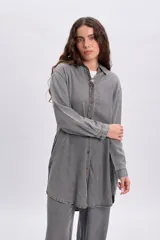 Camisa de jean de corte oversize y largo tipo túnica en color gris desgastado, con mangas largas, cuello camisero y cierre frontal de botones.