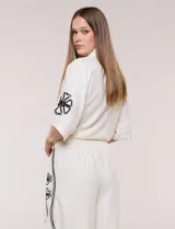 Conjunto de dos piezas negro compuesto por camisa de manga corta con cuello camisero y pantalón palazzo de tiro alto. Presenta detalles de bordados florales en contraste a lo largo de los laterales del pantalón y en las mangas.