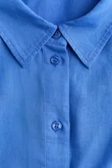 Camisa de lino y viscosa color azul, de corte oversized y diseño liviano, con cuello clásico, cierre frontal de botones, hombros caídos y mangas largas con puños abotonados.
