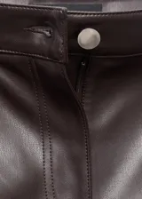 Pantalón de tiro medio con diseño flare, confeccionado en tejido efecto piel. Cuenta con cierre de botón y cremallera, trabillas para cinturón y cinco bolsillos funcionales.