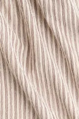Pantalón amplio de punto, tiro alto, con cintura elástica y cordón ajustable. Presenta un diseño de rayas verticales en tonos beige y marrón claro.
