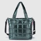 Bolso tipo tote de diseño acolchado con acabado brillante, color verde oscuro. Cuenta con doble asa superior y correa ajustable extraíble, cierre principal y logo de la marca en el frente.