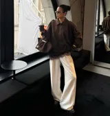 Chaqueta tipo bomber de color marrón, confeccionada en gamuza, con cuello camisero, mangas amplias y corte holgado a la cintura.