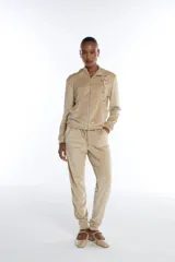 Pantalón jogging de terciopelo color beige, con silueta relajada, cintura elástica con cordón de ajuste y puños en los tobillos.