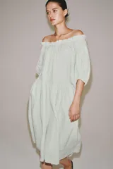Vestido midi confeccionado en lino 100%, con escote recto elástico estilo hombros descubiertos, mangas abullonadas y detalle de pliegues en la cintura. Cuenta con bolsillos laterales ocultos y bajo asimétrico.