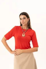 Remera de cuello redondo y manga corta, confeccionada en tejido elástico con un acabado suave y un leve brillo. Presenta un diseño básico con un pequeño isotipo bordado en la espalda.