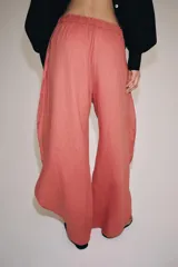 Pantalón confeccionado en lino 100%, de tiro medio con cintura elástica ajustable mediante cordones y bajo redondeado con aberturas laterales.