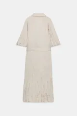 Vestido midi de Zara Woman Collection color beige, con cuello solapa, mangas por debajo del codo y diseño cruzado. Confeccionado en tejido plisado con brillo satinado, incluye un cinturón ajustable del mismo género con lazada en la cintura.