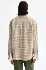 Camisa de sarga de algodón con estampado a cuadros en tonos beige y marrón, cuello americano, cierre frontal de botones, un bolsillo de parche en el pecho y mangas largas.