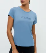 Remera deportiva Get Over de corte regular, confeccionada en tejido de poliamida con textura tipo crepé. Presenta cuello redondo, mangas cortas y estampa frontal con la palabra 'Athleisure'.
