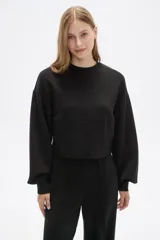 Buzo negro de corte cropped, con cuello redondo y mangas largas abullonadas.