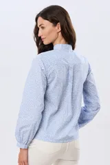 Camisa de algodón celeste con estampado floral pequeño, cuello mao, mangas largas con puños fruncidos y cierre frontal de botones.