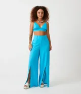 Pantalón pantalona de lino color celeste, de tiro alto, con bolsillos laterales y aberturas frontales en el ruedo.