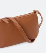 Bolso baguette pequeño color negro, con correa transversal ajustable y bolsillo interno con cremallera. Textura tipo saffiano y cierre por cremallera.