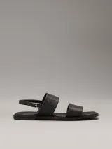 Sandalias planas Calvin Klein de cuero sintético negro, con puntera cuadrada, doble tira ancha y correa ajustable en el tobillo.