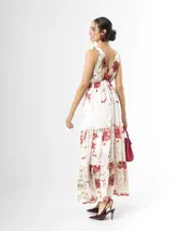Vestido largo confeccionado en mezcla de tencel y lino, con fondo off white y estampado floral en tonos rosados, rojos y verdes. Cuenta con escote en V pronunciado, breteles anchos ajustables con lazos en los hombros, corte bajo el busto y falda amplia con volados escalonados.