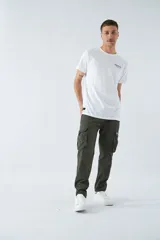 Pantalón cargo color beige, corte slim, con cierre y botón en la cintura, pasacintos, bolsillos cargo con botones y sin puños.