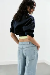 Jeans negro de tiro medio con corte balloon fit, diseño de cinco bolsillos y bajo acabado en puño con abertura y botón.
