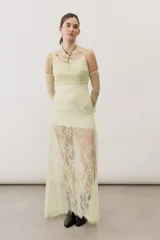 Vestido largo de encaje color blanco, con diseño de tirantes finos, escote cruzado y falda semi transparente.