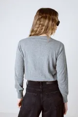 Cárdigan gris de punto con cuello redondo y cierre frontal con botones.