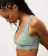 Top deportivo de microfibra color verde menta, con diseño de escote en V, banda elástica inferior ancha y detalles de tul en los breteles y laterales. Cuenta con copas estructuradas para mayor soporte.