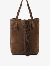 Bolso tipo bucket confeccionado en gamuza color marrón, con flecos aplicados a mano en el centro que aportan movimiento. Posee manijas para llevar al hombro, un sobre interno y una correa larga de terciopelo con detalles en gamuza.