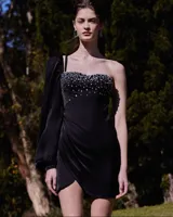 Vestido corto negro con escote corazón y corpiño estructurado con corsetería y aplicación de pedrería brillante. Posee una sola manga larga abullonada y falda cruzada estilo pareo.