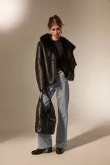 Bolso tipo hobo de gran tamaño, color negro, con diseño trenzado en la parte frontal y base lisa. Cuenta con un asa integrada para llevar al hombro.