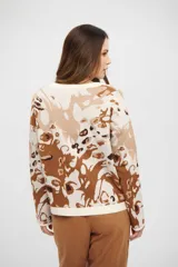 Buzo de tejido de punto con diseño abstracto en tonos tierra, cuello redondo y mangas largas. Presenta terminaciones acanaladas en puños y ruedo.