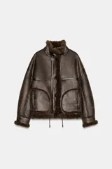 Chaqueta bomber de cuello alto con forro interior de pelo sintético. Presenta cierre frontal con botones, bolsillos delanteros y bajo ajustable con cordones.