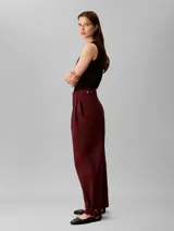 Pantalón chino de pierna ancha y talle alto Calvin Klein, color bordó, con cierre de doble botón y cremallera, bolsillos laterales y detalles de costura frontal.