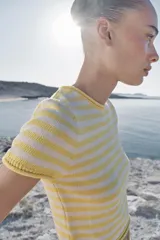 Top corto de punto con diseño a rayas horizontales en color amarillo y blanco, cuello redondo y manga corta.