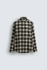 Camisa de corte relaxed fit confeccionada en una mezcla de lana y algodón. Presenta un diseño de cuadros, cuello solapa, manga larga con puños abotonados y cierre frontal con botones.