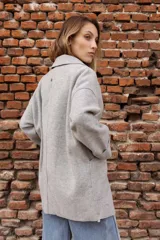 Tapado de paño color rosado, de corte oversized y diseño cruzado. Presenta solapas clásicas, mangas largas con puños vueltos y amplios bolsillos delanteros. Cierre frontal con un botón visible.