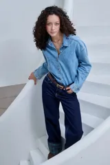 Campera de jean azul de corte holgado, con mangas largas y cierre frontal de botones metálicos.