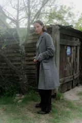 Tapado de corte recto y largo midi, confeccionado en tejido con textura de espiga en tonos grises. Presenta solapas clásicas, cierre frontal con botones y bolsillos laterales amplios con solapa.