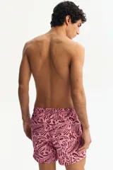 Short de baño rosado con estampado tropical en tono bordó, elástico revestido y cordón ajustable en la cintura, bolsillos laterales y suspensor interior de malla.