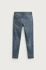 Jeans skinny fit de color azul, con efecto lavado y detalles de roturas en las piernas. Diseño de cinco bolsillos, tiro medio y cierre frontal con cremallera y botón.