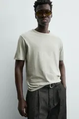 Camiseta de corte relajado (relaxed fit) color blanco roto o crema, con cuello redondo y manga corta.