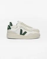 Championes urbanos Veja modelo V-90, confeccionados en cuero blanco con detalles en gamuza beige y logo V en color verde oscuro. Presentan suela de goma en tono crema y refuerzo en el talón con el nombre de la marca.