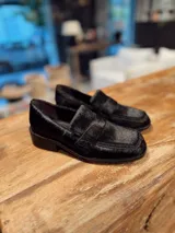 Mocasín de mujer en color negro, confeccionado en cuero con textura de pelo, diseño clásico con banda frontal y suela de taco bajo.