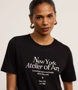 Remera negra de algodón con cuello redondo y mangas cortas. Estampa frontal con texto "New York Atelier of Art".