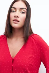 Blusa roja con textura de lunares, escote en V y mangas largas abullonadas.